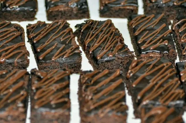 Rich fudgy chocolate brownies cut into squares with decorative chocolate drizzle on top, arranged on white parchment paper for birthday celebrations