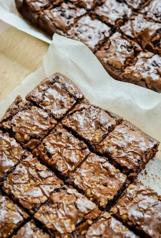 Homemade walnut brownies cut into squares on parchment paper, showing fudgy texture and nuts for easy birthday party serving