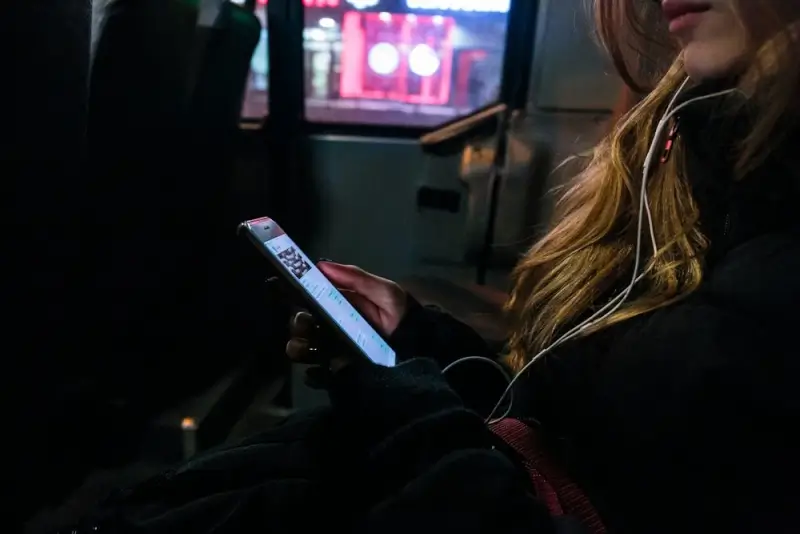Passenger using smartphone and headphones for entertainment during comfortable ottawa to montreal by bus journey at night