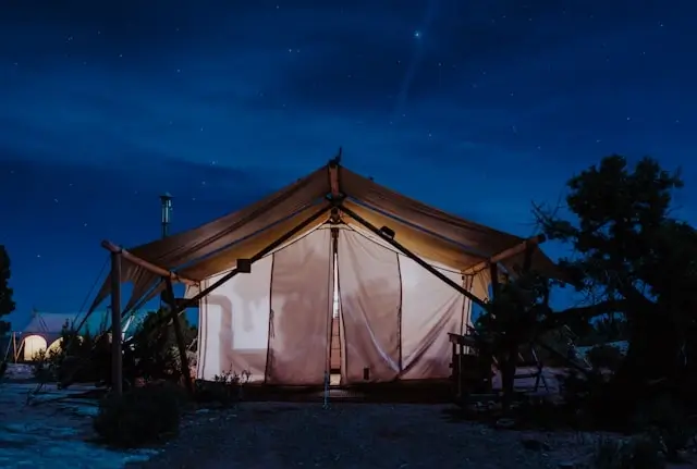 Coody tent illuminated at night under starry sky, showing durable camping tent structure perfect for outdoor adventures and base camp setups