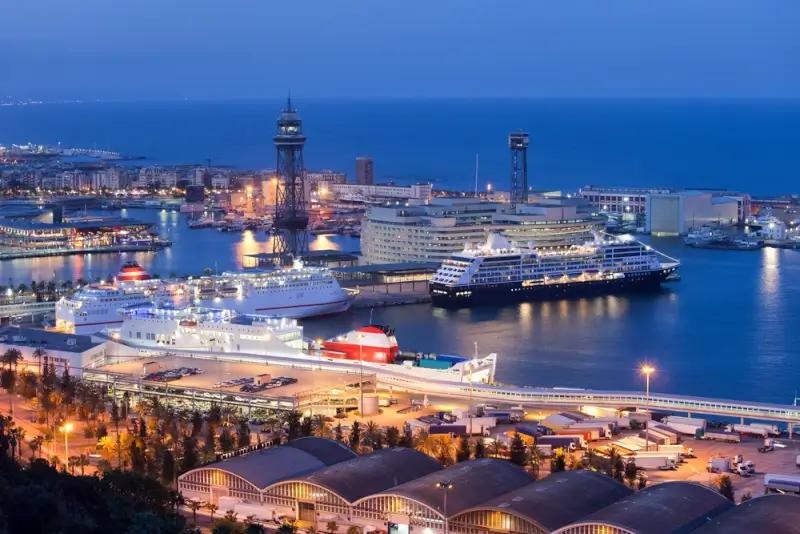 Barcelona cruise port at twilight with luxury cruise ships docked and illuminated Mediterranean coastline, a popular destination on Southampton UK cruise itineraries