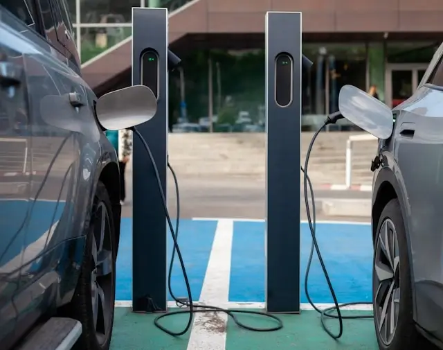 Two electric vehicles charging at modern EV charging station with dual charging ports and cables