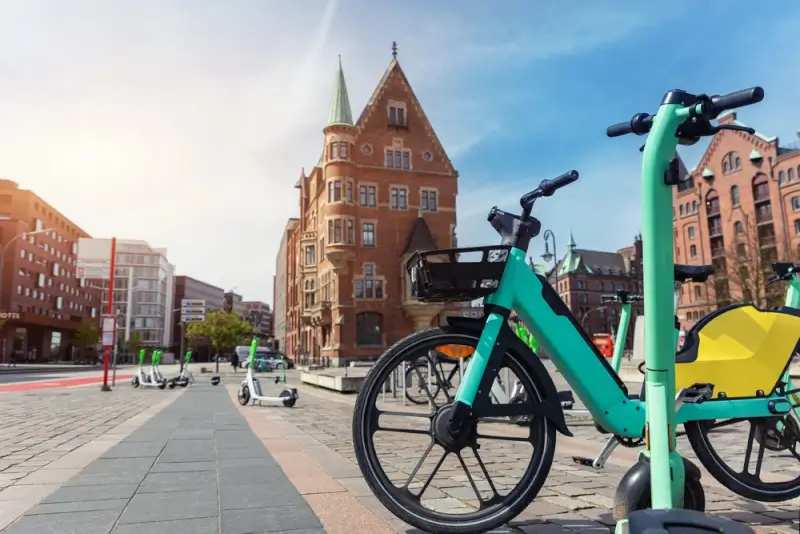 Green electric bike sharing station in historic German city square with traditional brick architecture