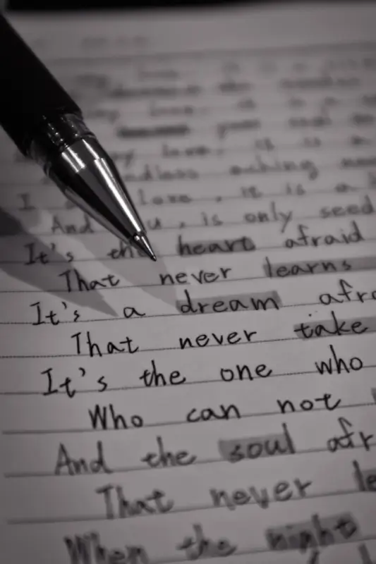 Close-up of pen on handwritten essay draft with lined paper showing academic writing process