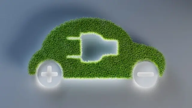 Green grass-covered car silhouette with electric plug symbol representing eco-friendly sustainable transportation