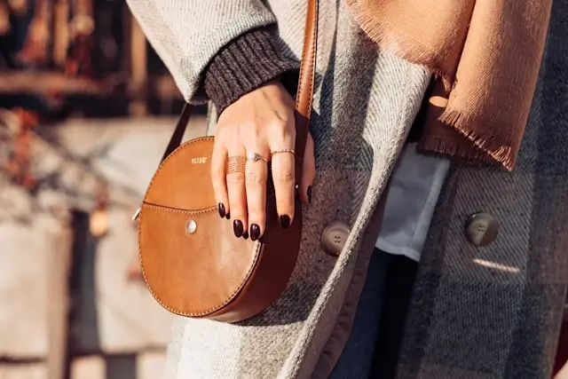 Close-up of woman in gray sweater dress with brown leather handbag and scarf - stylish fall dress ideas with accessories