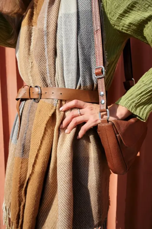 Close-up of woman in striped maxi dress with brown leather belt and crossbody bag - accessorized fall dress ideas styling