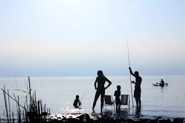 Digital nomad family fishing together at sunset lake, creating memorable experiences while traveling and worldschooling children