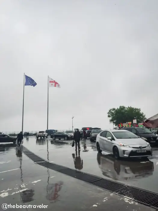 Sarpi border crossing between Turkey and Georgia with EU and Georgian flags, cars and travelers on rainy day