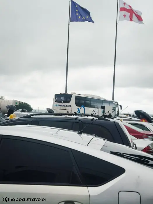 Luks Karadeniz bus at Sarpi border crossing with EU and Georgian flags, cars waiting for Turkey-Georgia immigration clearance