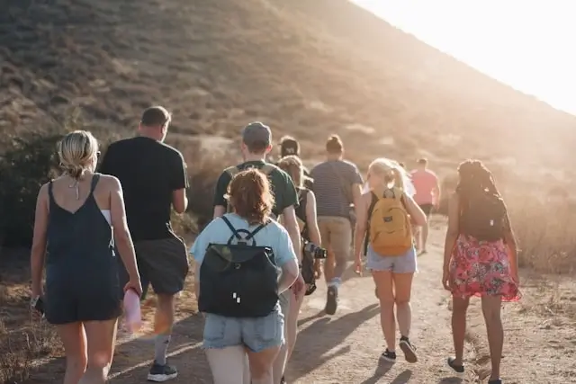 Group of travelers hiking together on mountain trail during sunset, showing benefits of group tours for solo female travelers