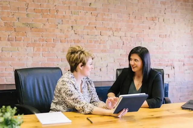 HR manager interviewing payroll candidate across conference table with tablet and documents in modern office