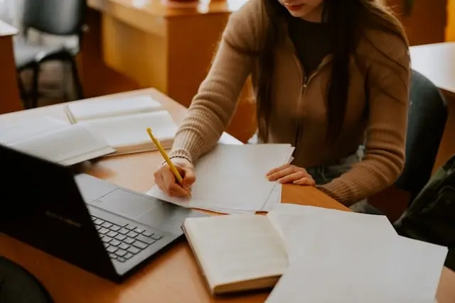a female student writing a note for her essay writing task
