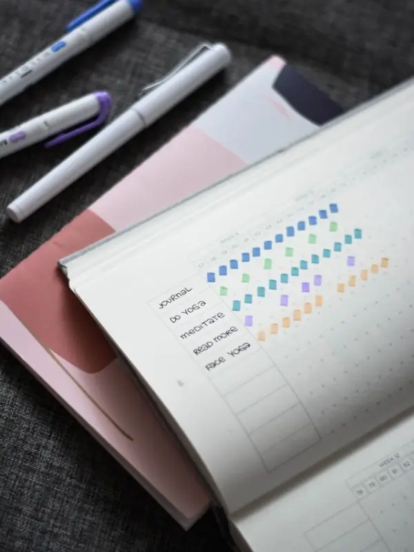 Colorful habit tracker chart in notebook with pens showing daily routine progress tracking system