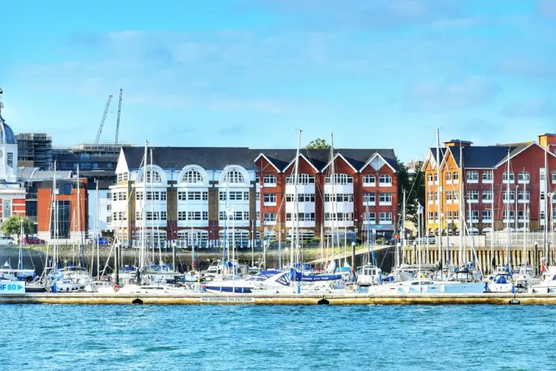 Colorful waterfront buildings and marina in Southampton UK with sailing boats, showcasing the charming port city departure point for European cruises