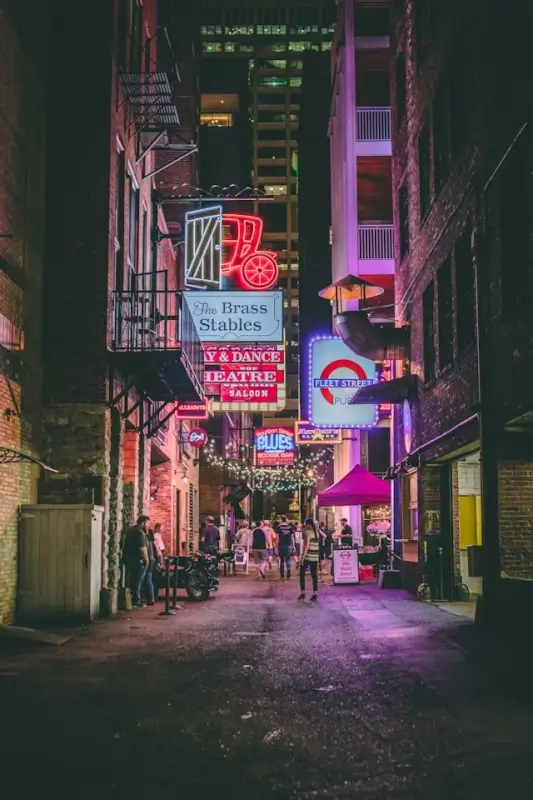 Nashville Printer's Alley nighttime scene with neon bar signs and crowds perfect for bachelorette party bar hopping