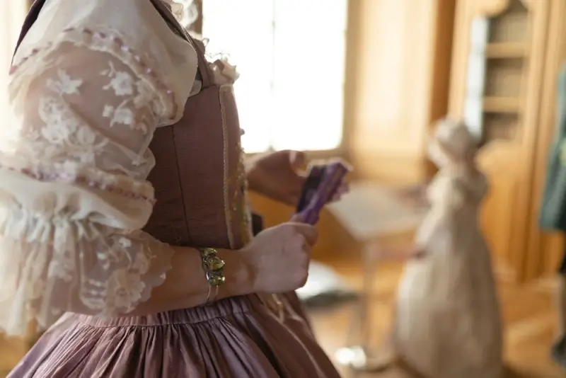 Woman wearing brown Renaissance corset with white lace sleeves and gathered skirt, showcasing fitted bodice style in period setting