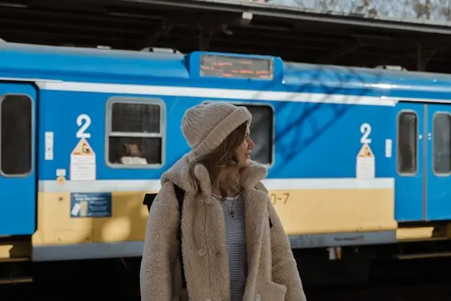 Solo woman traveler standing near blue public train, demonstrating safe public transportation options for female travelers