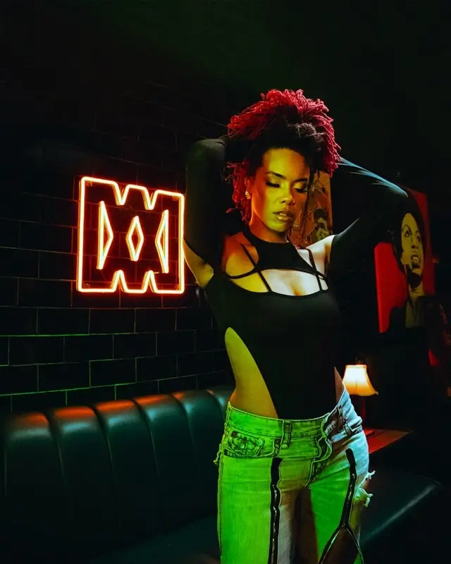 Woman in black cutout bodysuit styled for nightlife travel experiences in urban setting with neon lights