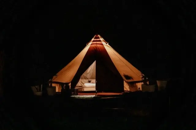 Coody tent glowing at night with open entrance showing spacious interior and comfortable bed, ideal camping tent for beginner campers