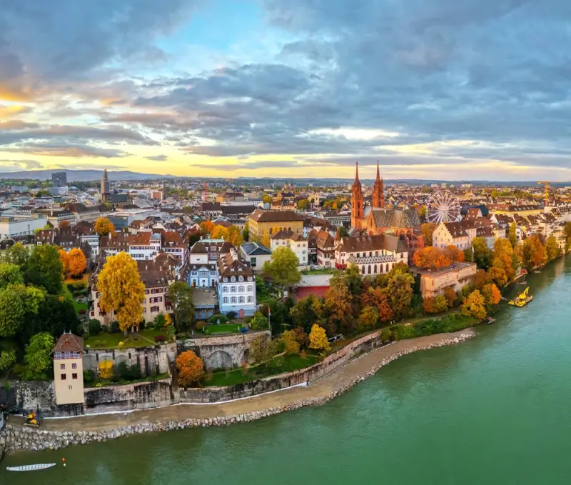 Historic Basel skyline with traditional architecture and riverfront buildings during autumn sunset