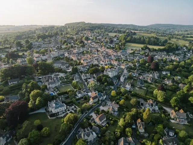 Aerial view of picturesque Cotswolds village with honey-colored stone houses and rolling green countryside perfect for Cotswolds tourism