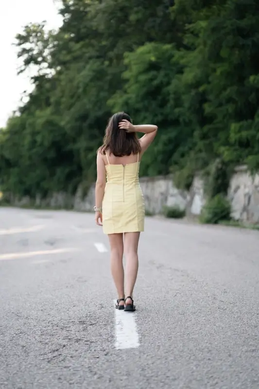 Woman wearing square neck bodysuit under yellow dress while exploring outdoor travel destinations