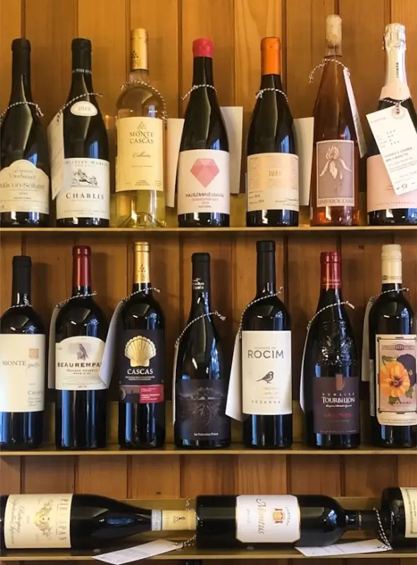 Curated fine wine collection displayed on wooden shelves featuring French wines including Chablis and Burgundy bottles, representing a well-organized wine cellar for collectors