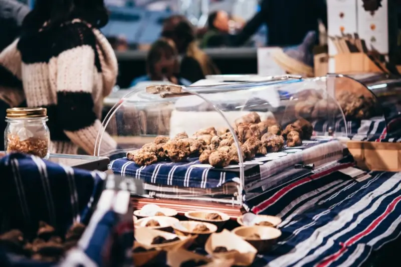 Italian truffle market stall with fresh truffles under glass cover during autumn harvest season