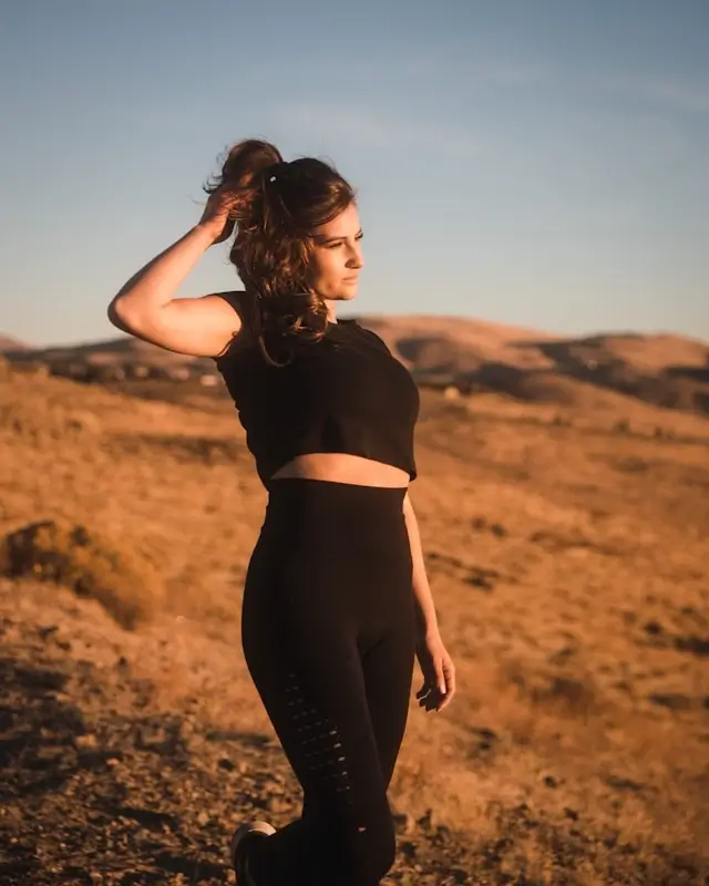 Woman wearing black cotton leggings and crop top in desert landscape during golden hour sunset
