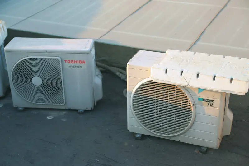Two outdoor heat pump condenser units installed on residential patio showing fan grilles and inverter technology