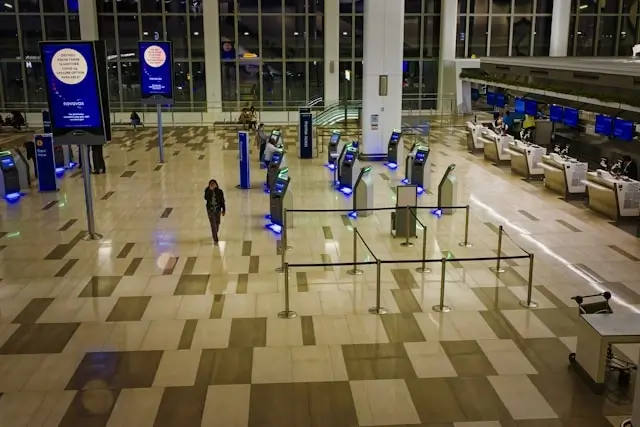 Modern airport terminal with automated biometric security checkpoint kiosks and organized queue barriers for streamlined passenger processing