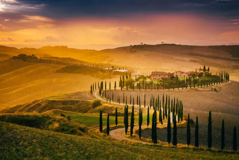 Tuscany autumn landscape with golden hills, cypress trees, and traditional Italian farmhouse at sunset