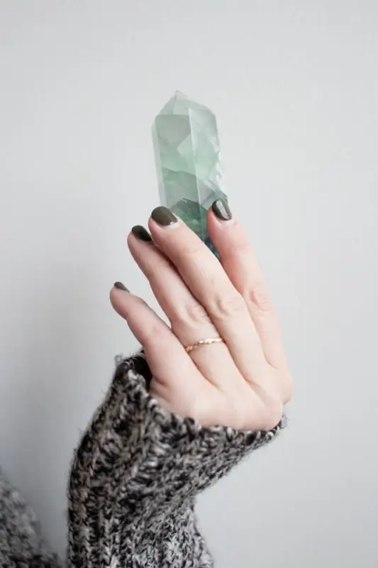 Hand holding transparent green fluorite crystal point showing natural clarity and color characteristics for authentic crystal identification and gemstone analysis