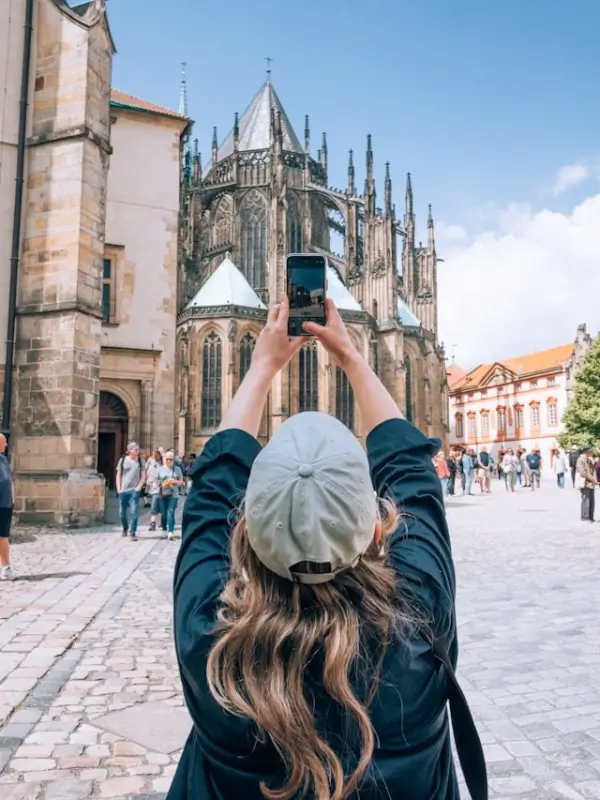 Tourist taking photo of historic Gothic cathedral in European town square on affordable weekend trip
