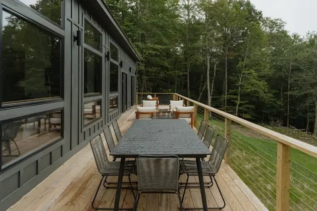 Modern garden pods with expansive wooden deck featuring outdoor dining table and chairs surrounded by forest trees for staycation retreats