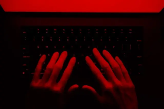 Hands typing on laptop keyboard under red lighting, illustrating cybersecurity risks of unsecured hotel Wi-Fi networks