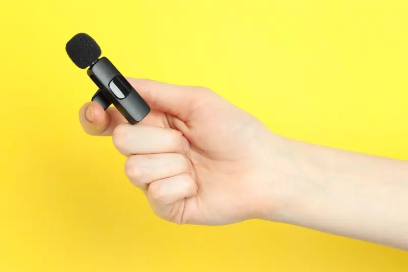 Hand holding compact wireless microphone transmitter with foam windscreen - BOYA wireless mic for mobile vlogging