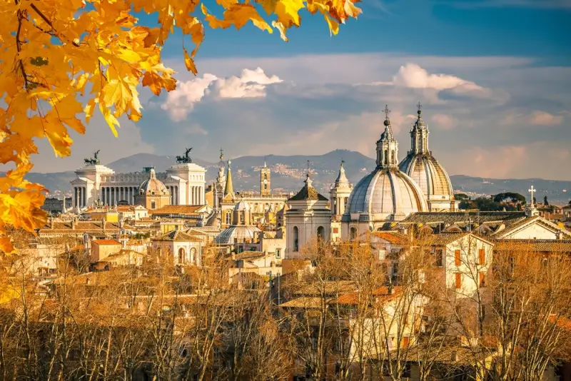 Autumn view of Rome with golden leaves and historic Italian architecture including church domes and monuments