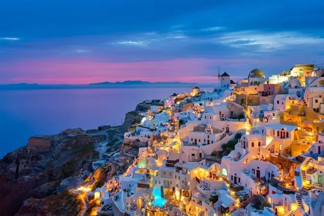 Oia village Santorini Greece at sunset with whitewashed buildings and blue domes overlooking Aegean Sea - iconic Greek island destination