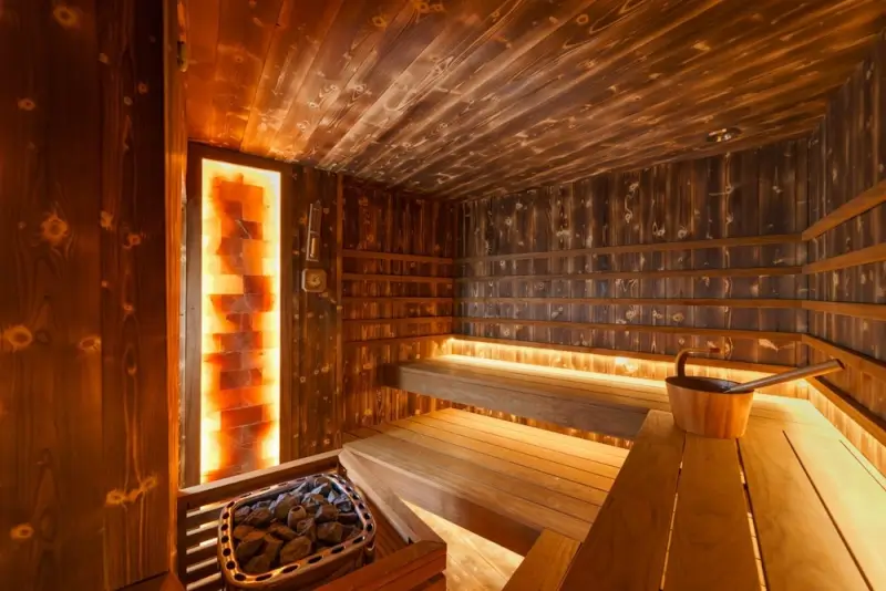 Traditional Finnish sauna interior with wooden benches, salt wall, and heating stones at Crane Lake Minnesota lodge