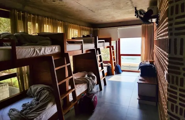 Budget hostel dorm room with wooden bunk beds and luggage for affordable weekend accommodation