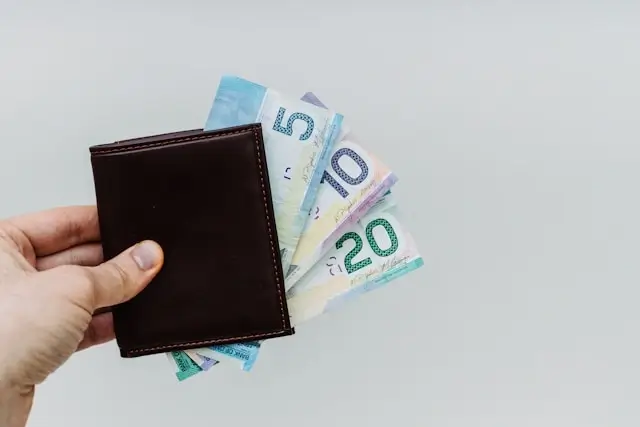 Hand holding wallet with colorful bills showing budget planning for weekend getaway travel