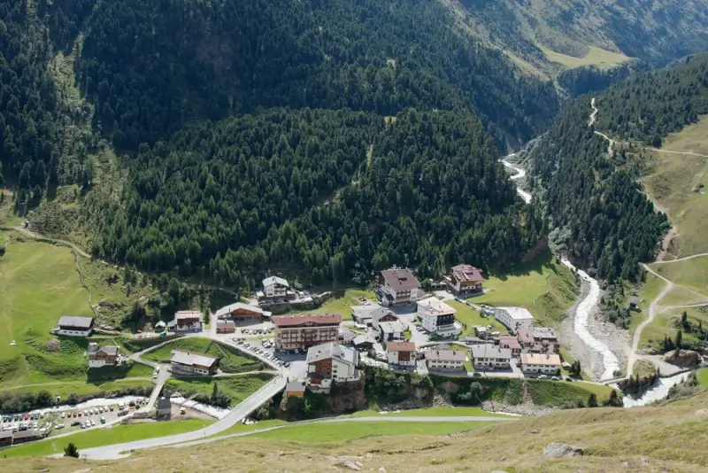 Aerial view of Vent village nestled in mountain valley with traditional chalets, winding river, dense forests, and pastoral meadows surrounding the compact settlement