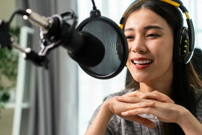 Female content creator recording podcast with professional microphone and headphones - indoor studio setup for voiceovers