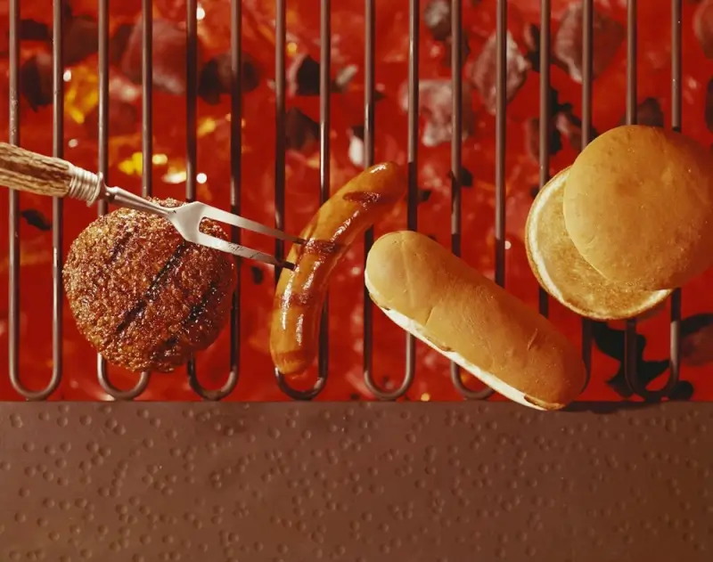 Grilled burger and hot dog with buns on red grill grate at Crane Lake winter lodge restaurant