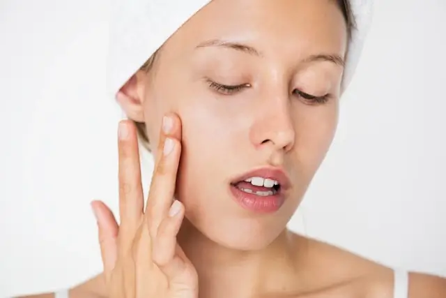 Woman gently applying face serum with fingertips demonstrating proper absorption technique for skincare routine