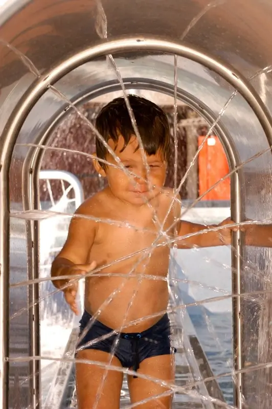 Young boy enjoying water spray feature at Swiss water park in Lugano, Ticino