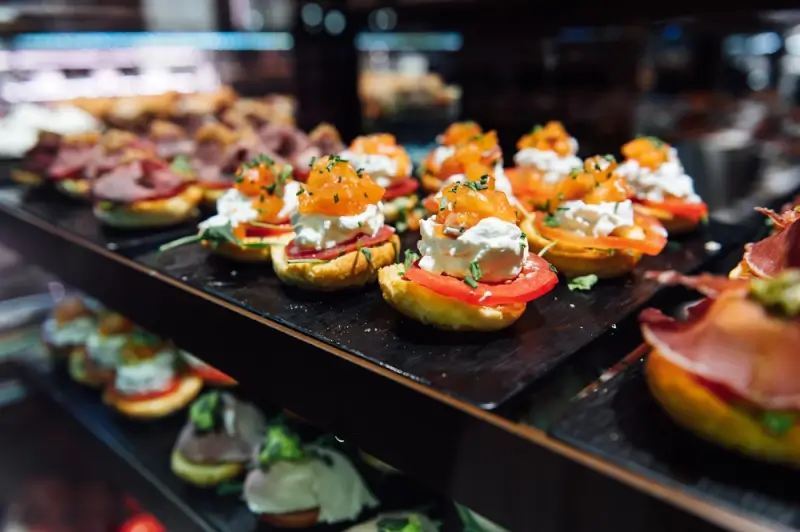 Colorful Spanish tapas with salmon, cream cheese, and tomatoes displayed on slate platters at San Miguel Market during a trip to Madrid