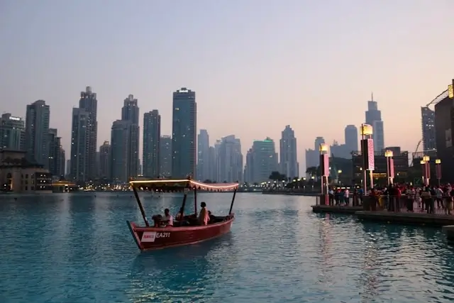Traditional abra boat ride on Burj Khalifa Lake at sunset with Downtown Dubai hotels and skyline in background
